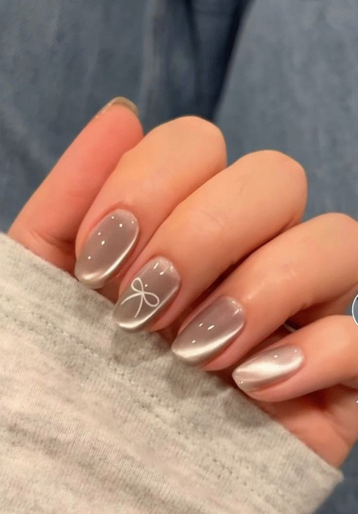 Silver chrome aura manicure with glossy glow and a tiny white bow accent—a Pinterest-ready look from trendy nail designs 2025.
