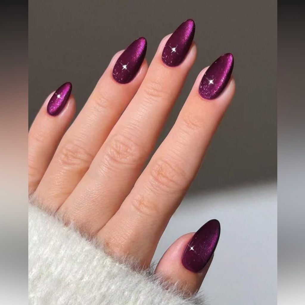 Deep plum cat-eye nails with magnetic velvet sheen and tiny star sparkle on almond shape.