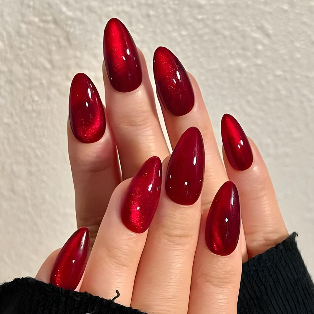 Ruby red aura nails with glossy jelly depth and soft pearl highlight, glamorous almond set.