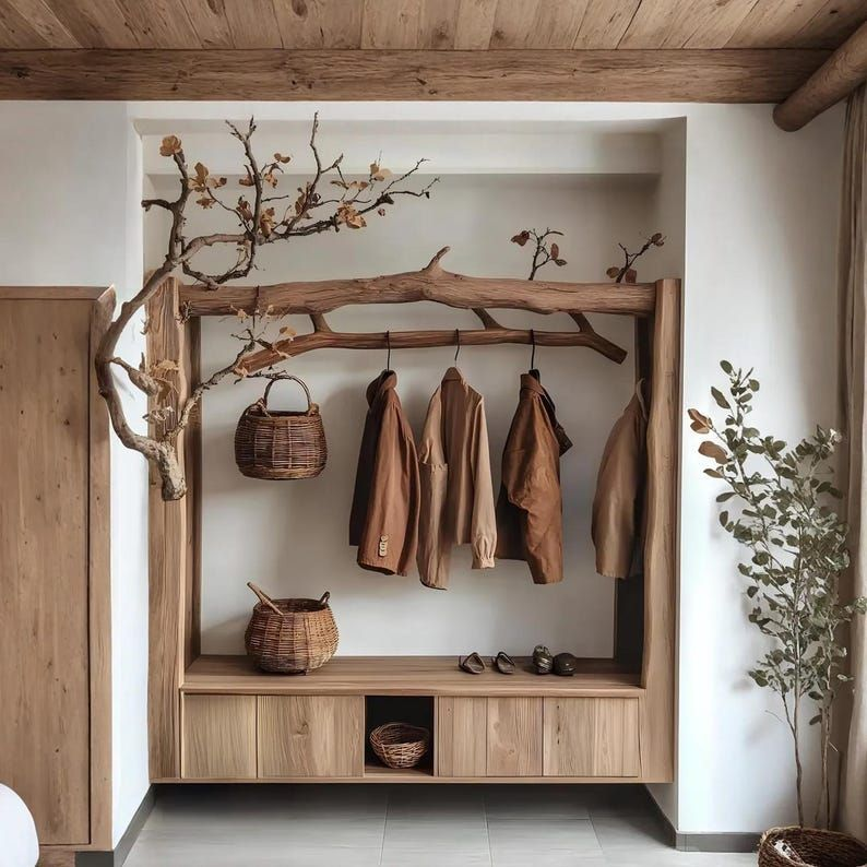Rustic wooden branch hanger with woven baskets and coats for natural wall decor.
