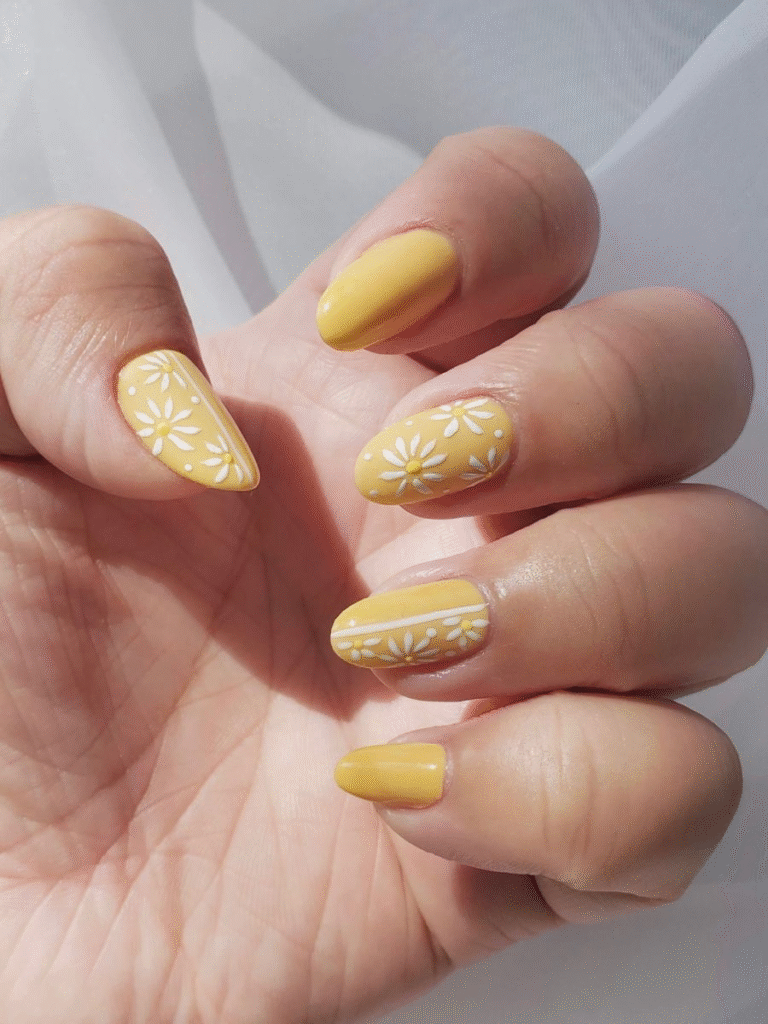pastel yellow sunflower nails with white daisy floral accents on almond shape, sunlight close-up