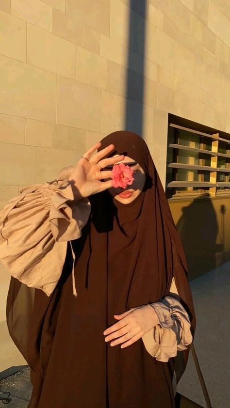 chocolate brown jilbab outfit at golden hour with blush sleeves, modest fashion holding a flower