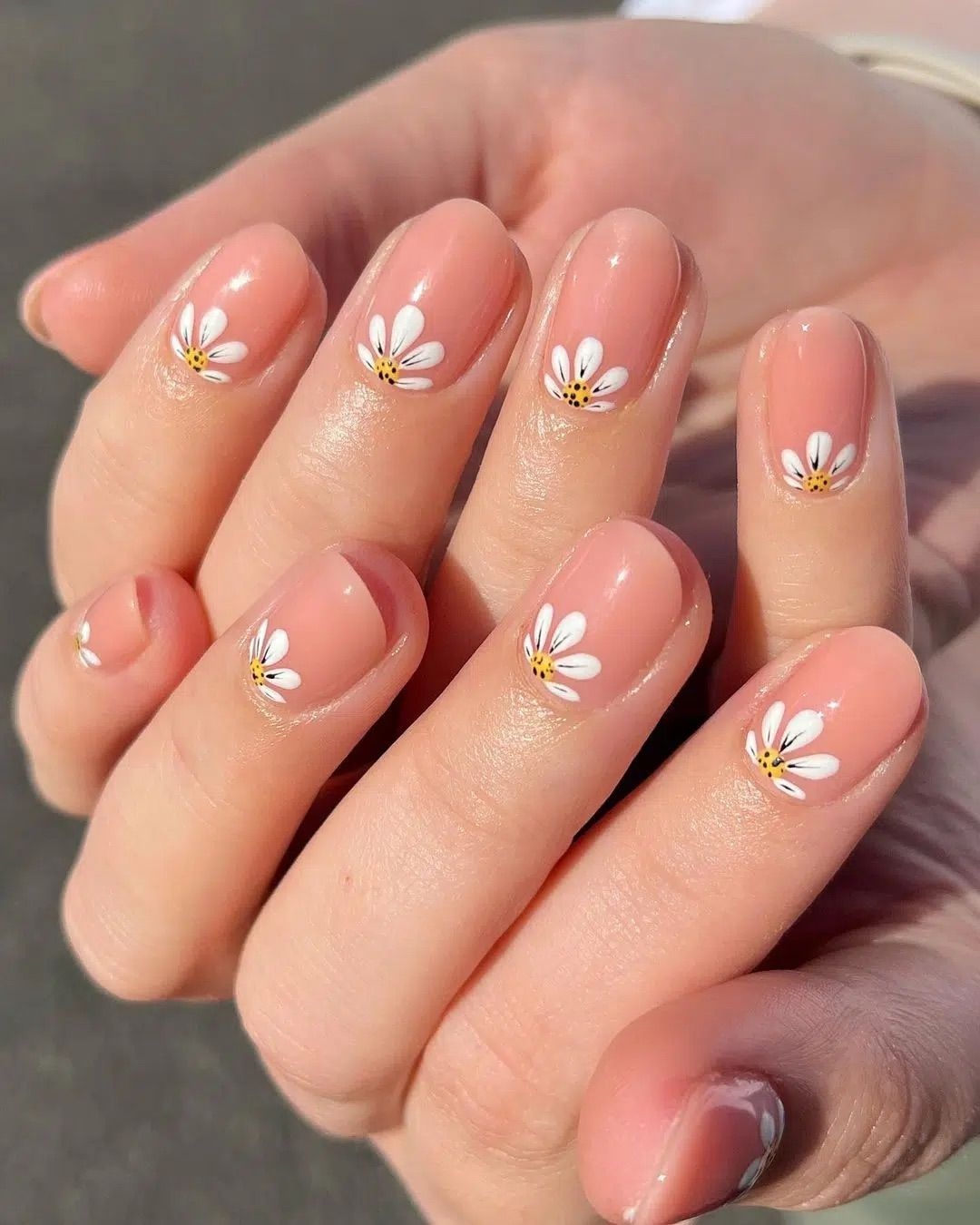 short peach jelly nails with small white daisies at cuticle, glossy oval
