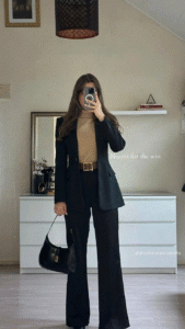 black blazer and trousers with camel turtleneck and statement belt, small black shoulder bag.