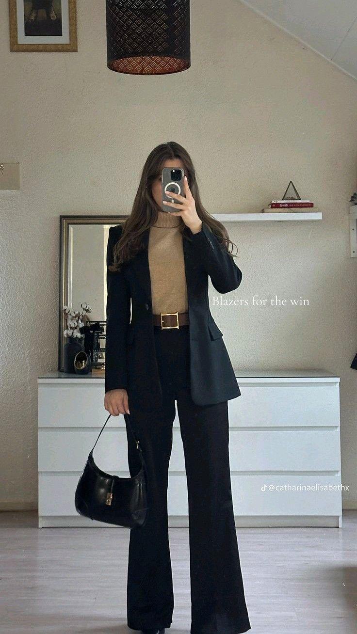 black blazer and trousers with camel turtleneck and statement belt, small black shoulder bag.