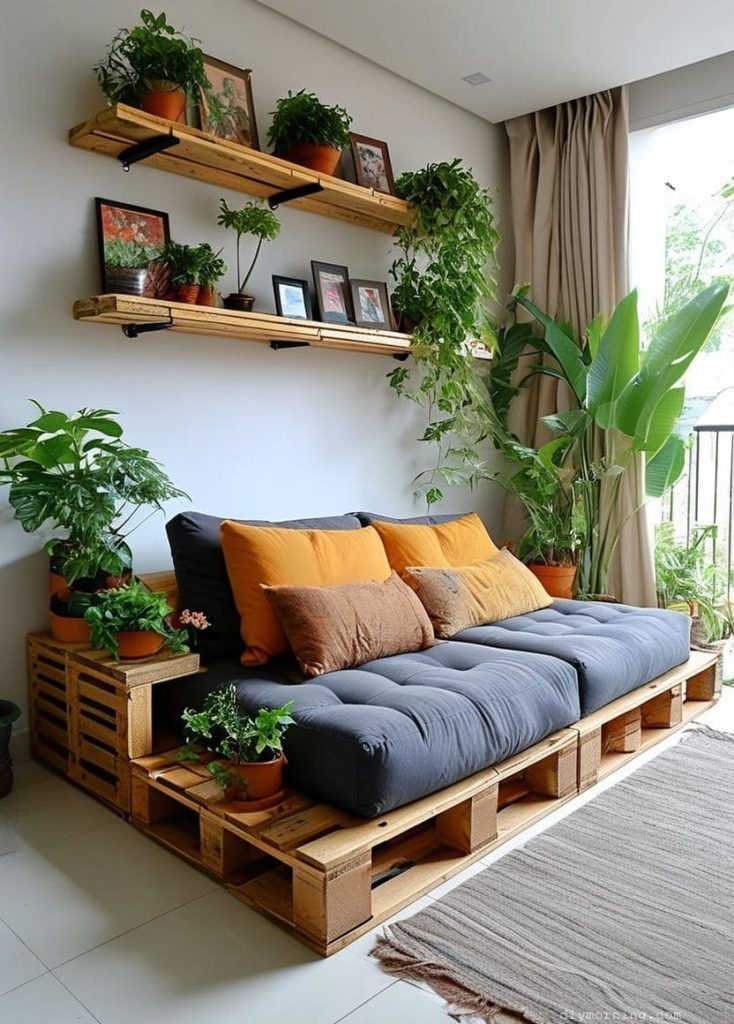 “DIY pallet sofa with grey cushions, wooden wall shelves and lush indoor plants—eco friendly living room home decor.”