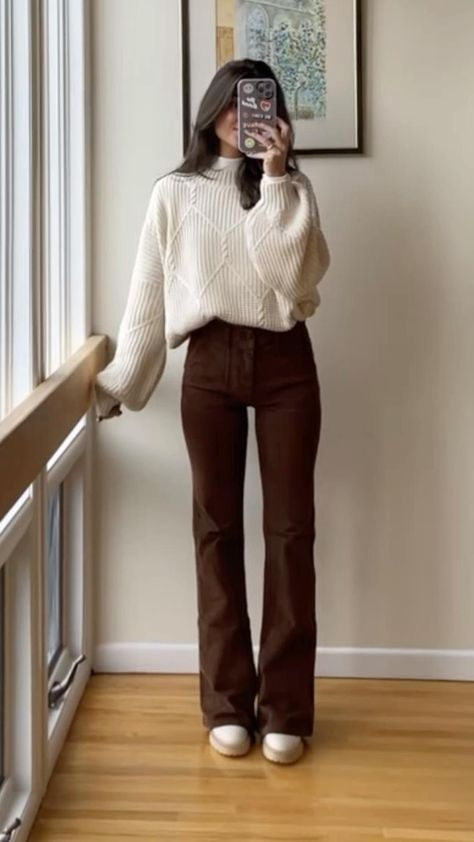 winter comfort dresses outfit — cream chunky sweater with high-waist chocolate brown flared pants and white sneakers by a window