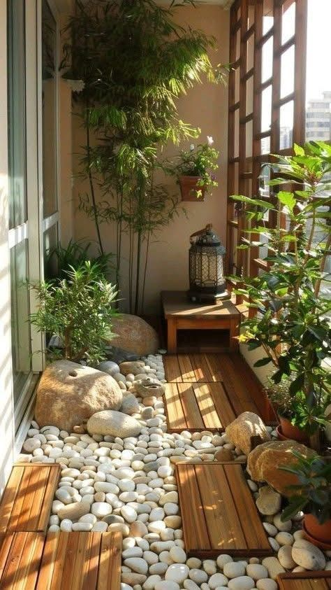 Zen balcony walkway with wood deck tiles, white river stones, lantern and lush green plants for a natural corridor feel.