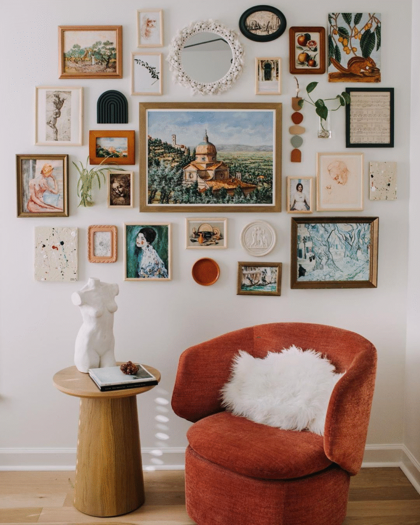Eclectic gallery wall of vintage art and mirror above a terracotta accent chair with white faux-fur pillow and a wooden side table with a bust sculpture.
