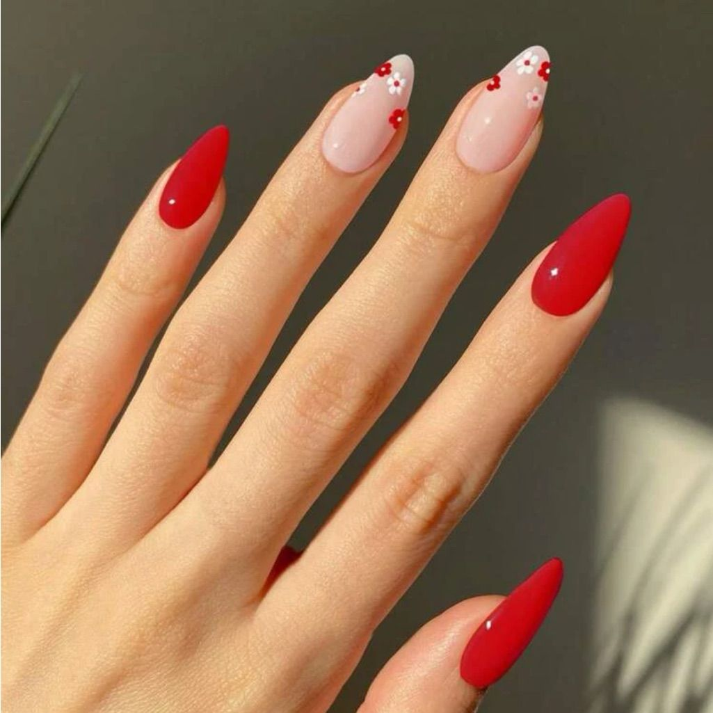 Bright red almond press on nails with two nude nails featuring tiny red blossom accents.
