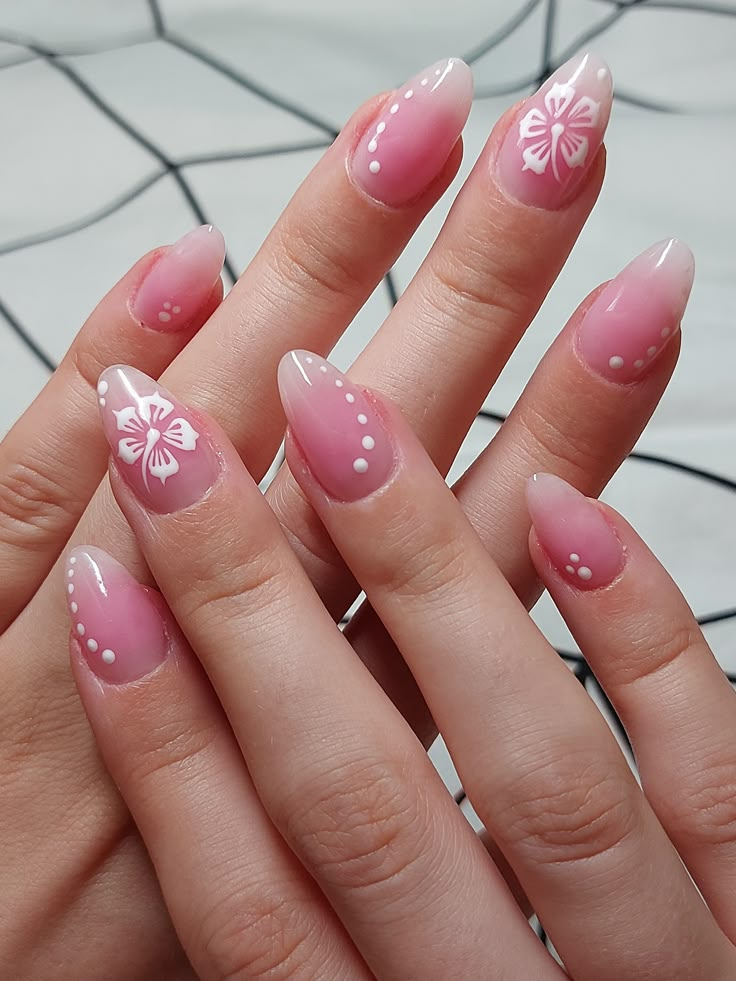Almond nails with sheer pink-to-white ombré tips, white hibiscus flowers and dotted accents for a tropical French look.