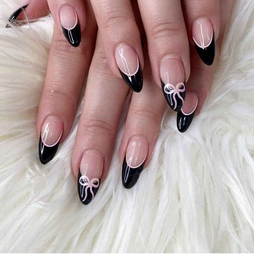 Black French manicure with pink outline and delicate bow detail on ring fingers.