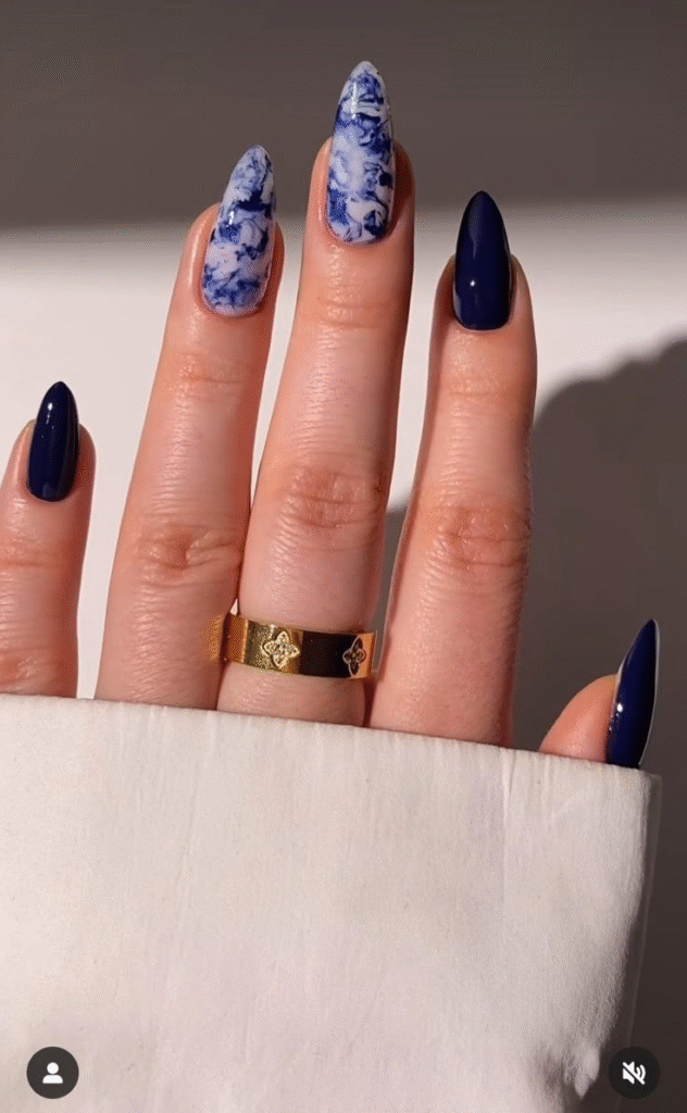 Almond nails alternating between solid sapphire gel and indigo-white marble; glossy topcoat.