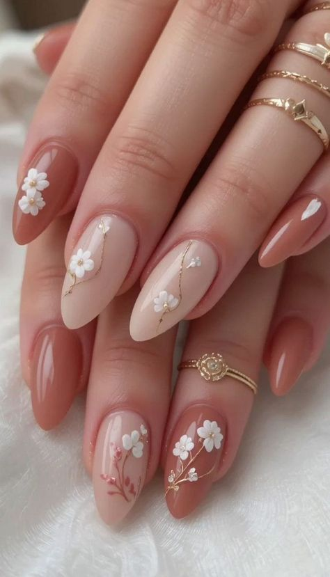 wedding Almond nails alternating terracotta and nude with small white blossoms and thin gold lines.