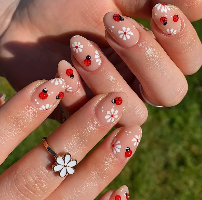 Bubblegum pink almond aesthetic nails with heart-shaped cherries on clear nails, styled with delicate gold rings and a pink knit sleeve.