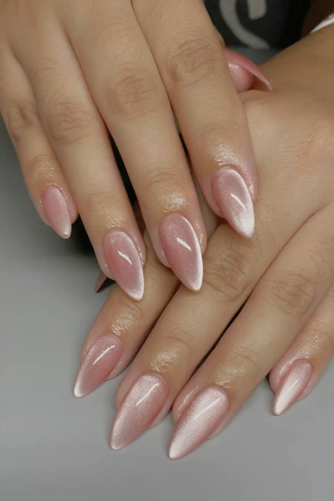 Soft pink cat eye nails on almond shape, glossy finish.