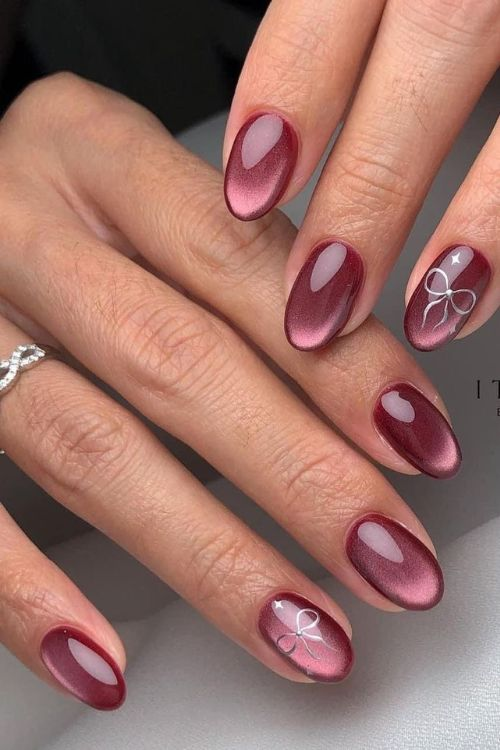 Burgundy magnetic manicure with bow accent.