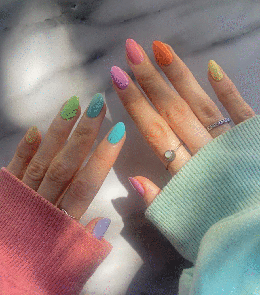 Pastel Skittle / Mismatched palettes nails in soft daylight with cozy sleeves.